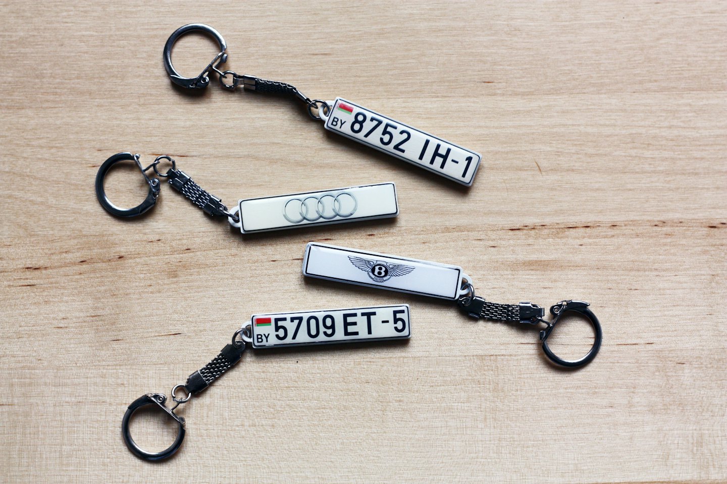 Three metal keychains on a light wood surface.